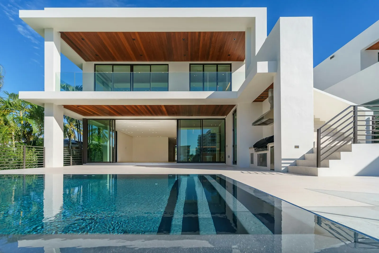 A modern white villa with a pool and deep overhangs.